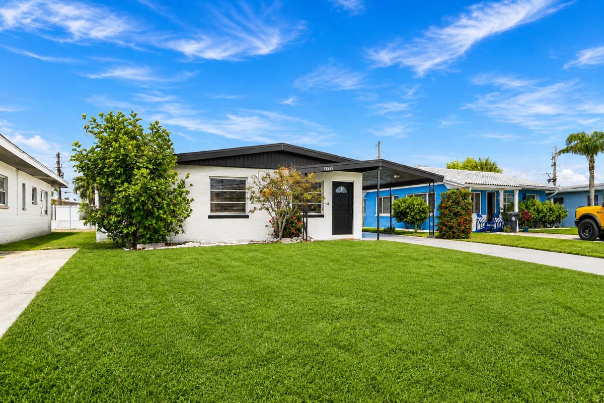 Wide front yard view featuring lush landscaping and modern single-story home design.