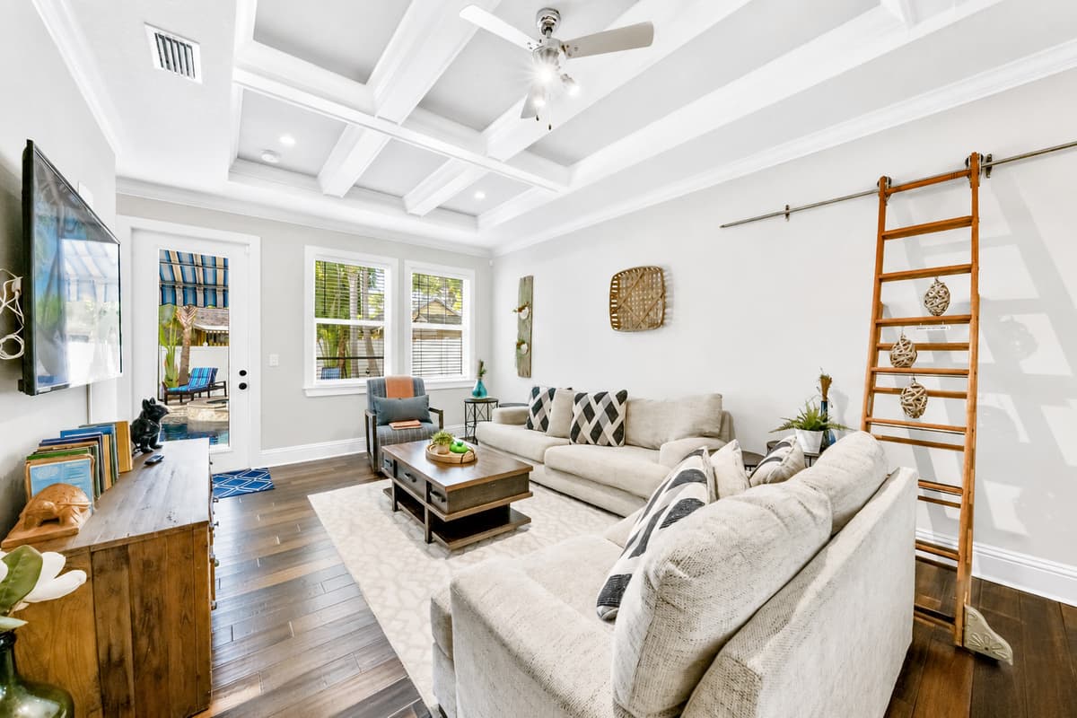 Relax in the open-concept living area with comfortable seating, high ceilings, and a large Smart TV.