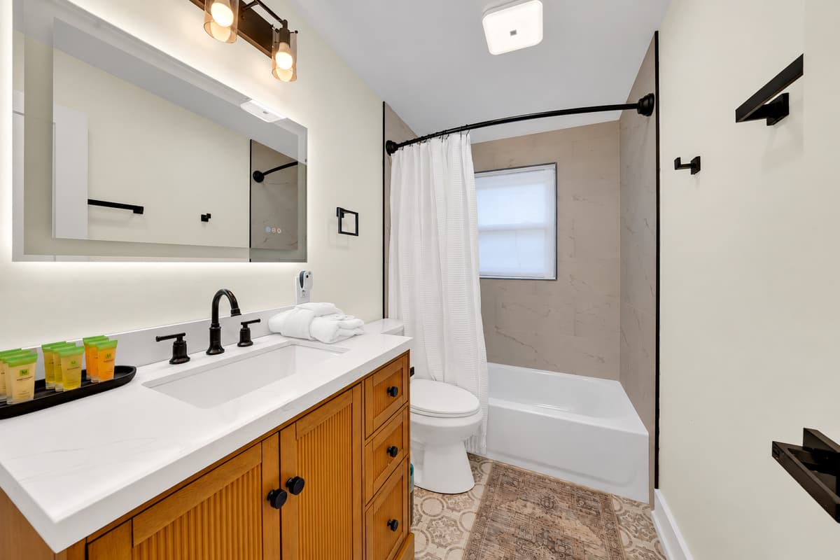 A tub for kids, a shower for everyone. Bathroom 2 has a wood vanity, a lighted mirror and a tub and shower combo. Fresh towels and toiletries are set out for your arrival.