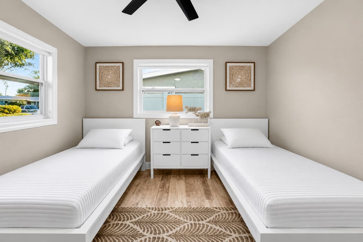Symmetrical twin bedroom layout with two single beds, large windows, and coastal-inspired decorative accents.