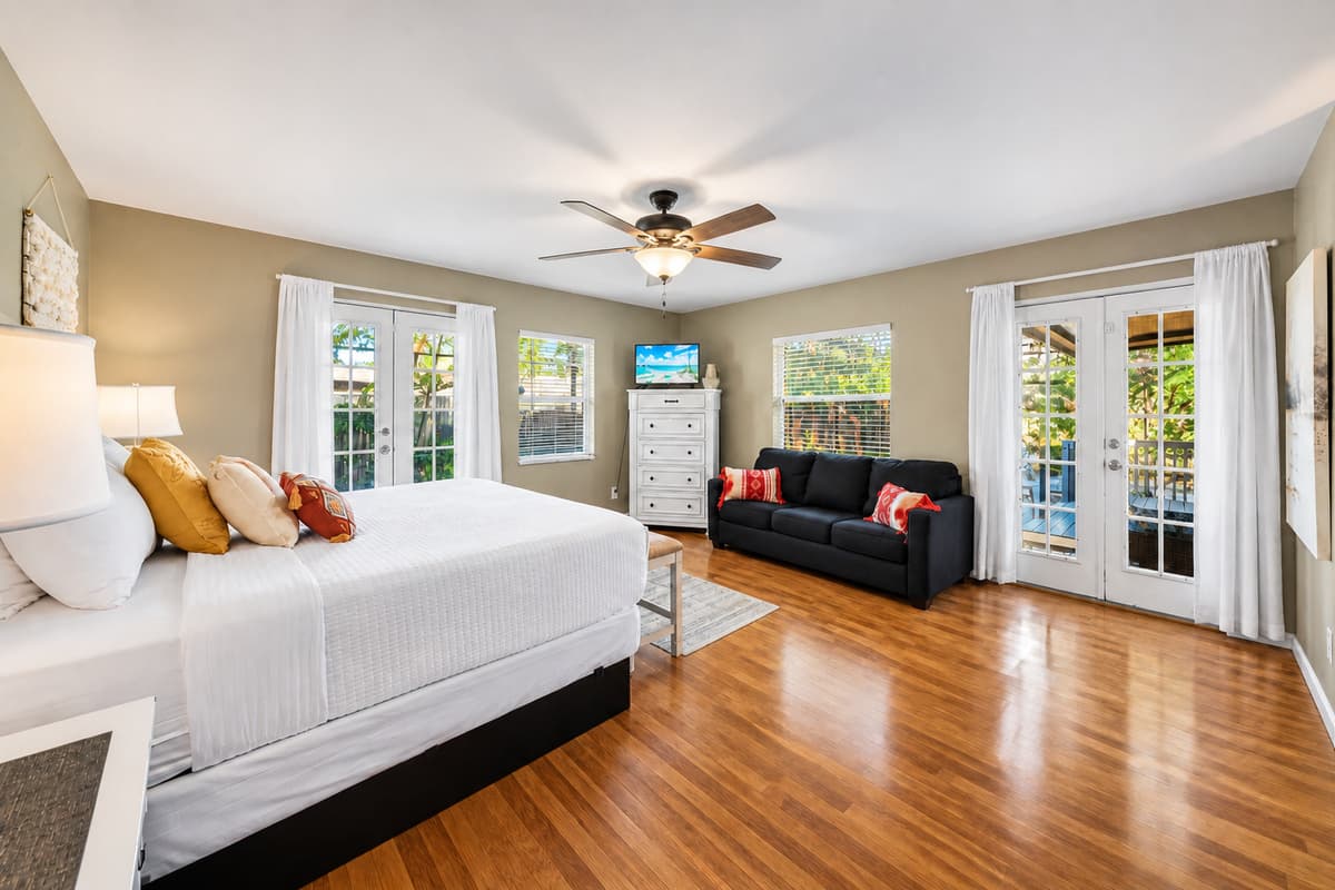 Expansive master bedroom with a king bed, sitting area, and oversized windows for natural sunlight.
