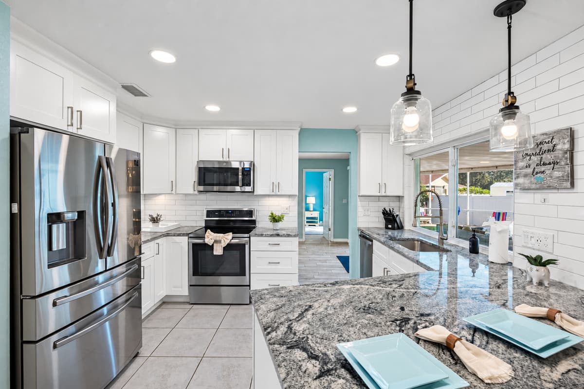 This modern kitchen blends style and function, featuring a spacious layout, bar seating, and plenty of natural light.