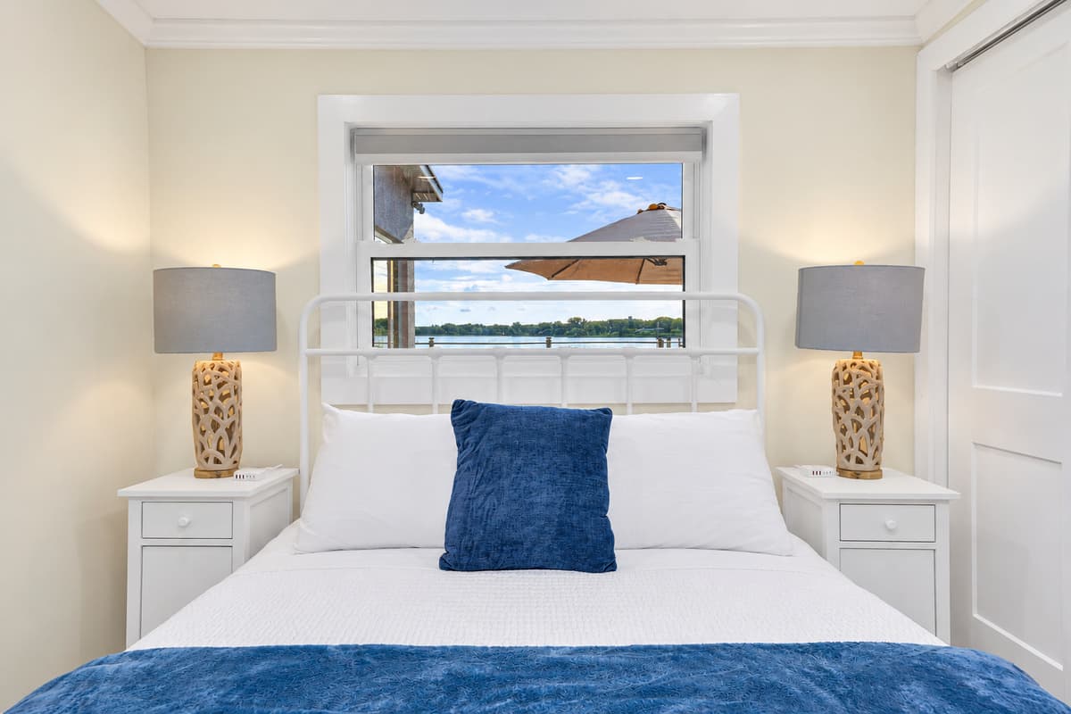 Queen bed with a peek of the water. A white metal queen bed with matching nightstands and a window view. Wake up and catch a glimpse of the bay.