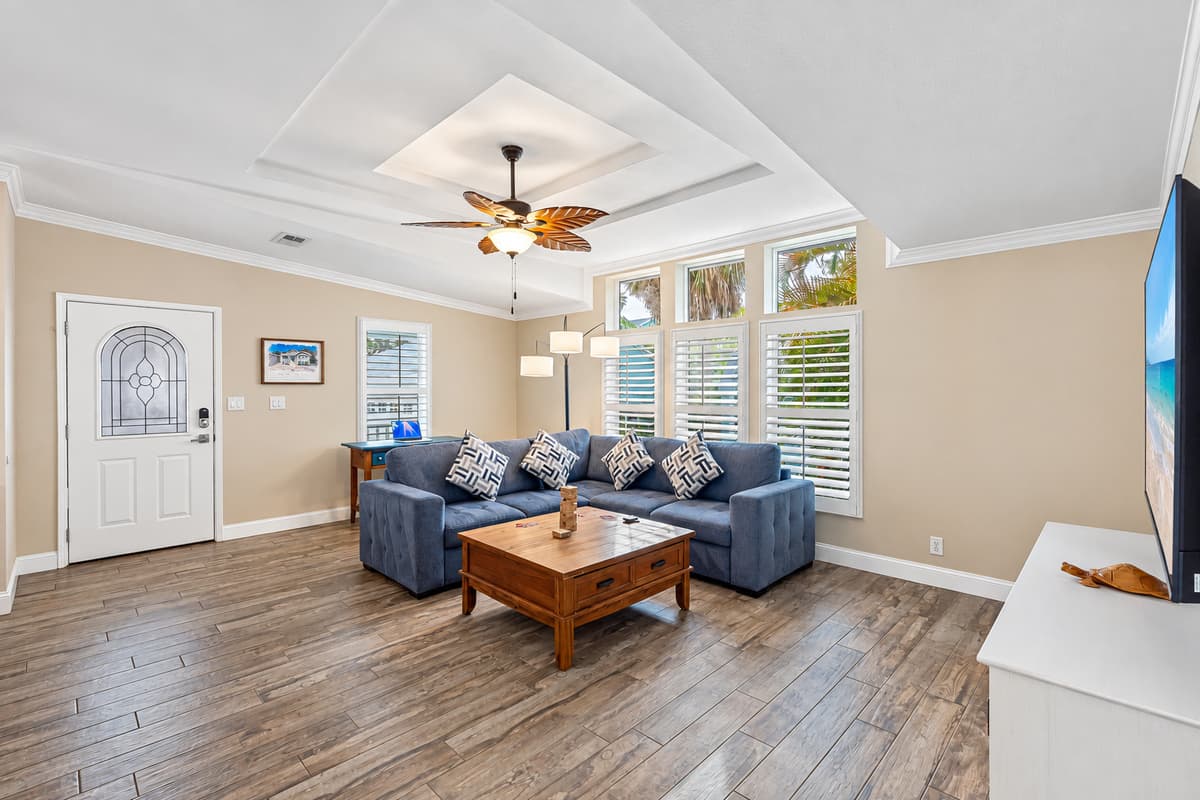 Relax in this beautifully designed living room, where large windows, soft tones, and a roomy sectional create the perfect spot to unwind after a day at the beach.