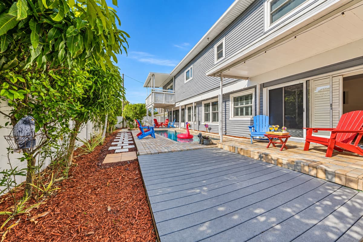Wide backyard perspective with walkway leading to the pool and seating areas—inviting and well-designed outdoor space 