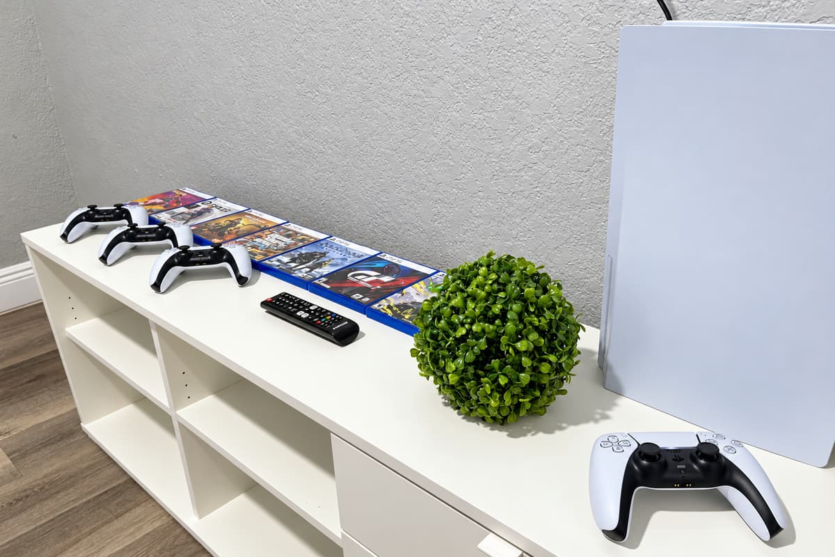 Four controllers, no waiting. PS5 with four controllers and a lineup of games on the stand. Everyone plays, nobody sits out. A favorite for kids, teens, and competitive dads alike.