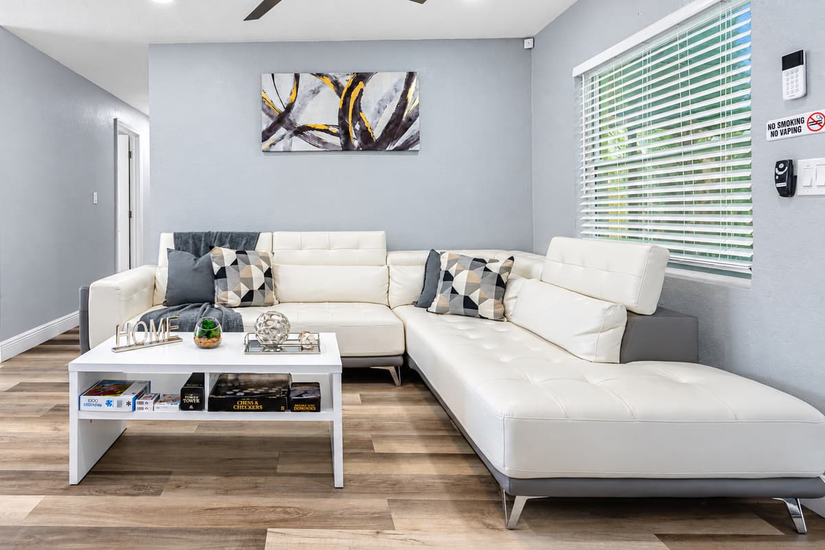 A sectional that seats the whole group. The white L-shaped sectional wraps the coffee table, with space for everyone to stretch out. Game night, movie night, or a lazy afternoon nap.