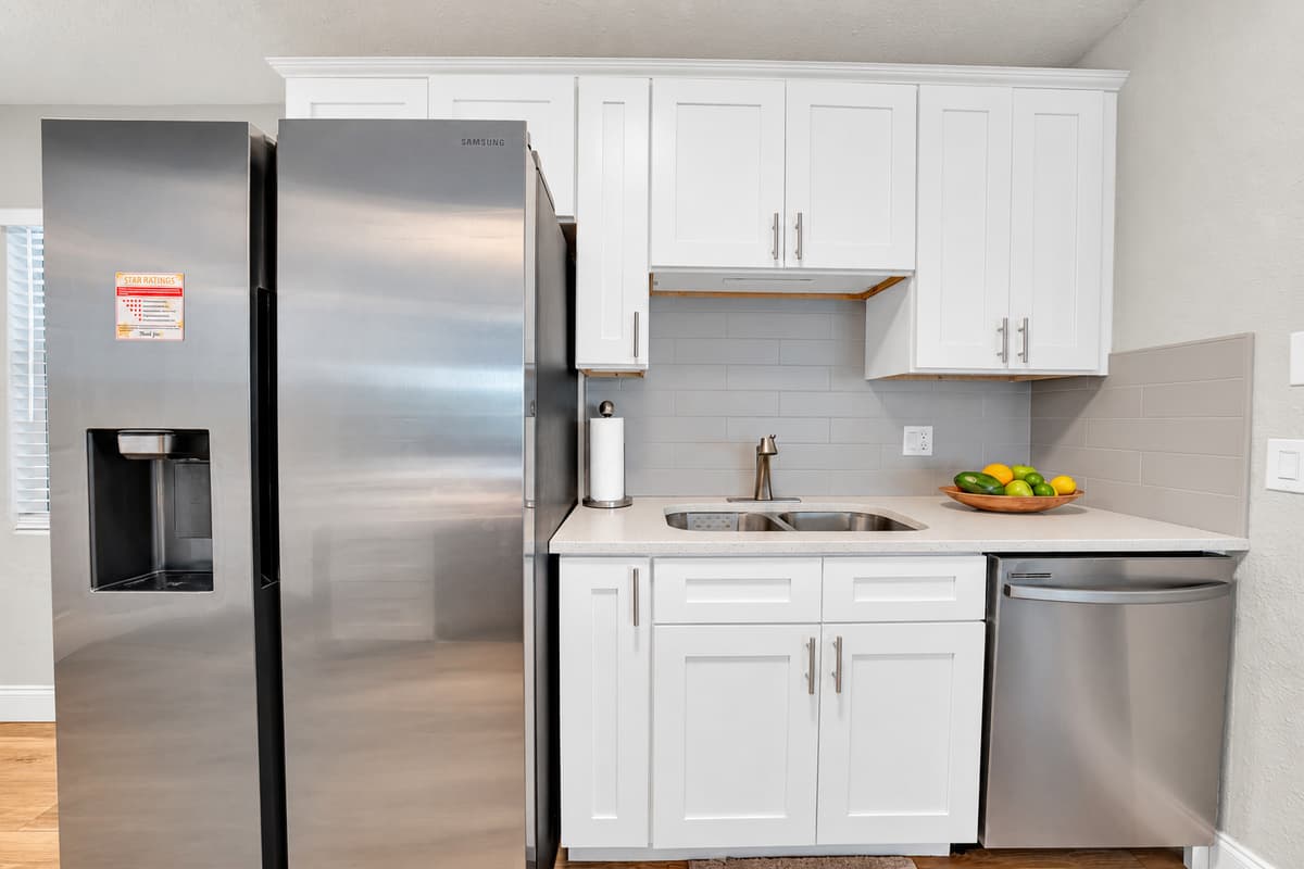 Stainless fridge with in-door ice and water, dishwasher beside the sink, white cabinets from end to end. Groceries on day one means breakfast is handled all week without a single line at a restaurant.