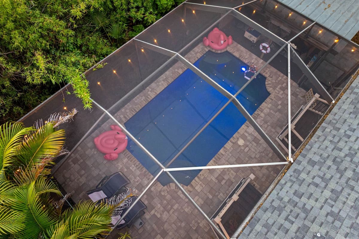A bright and airy pool area enclosed by screens and framed by lush foliage, offering the perfect blend of sunshine and seclusion.