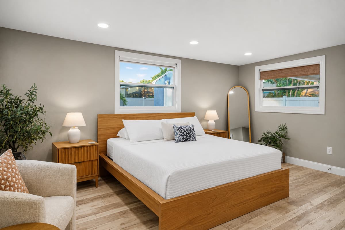 Bedroom featuring a comfortable bed, mirrored closet doors, beach-inspired artwork, and a bright, airy design.