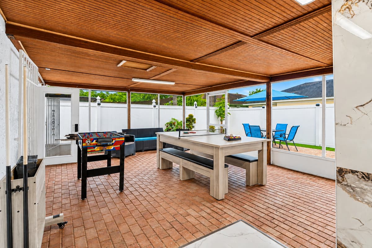 Outdoor entertainment oasis with pool table, foosball table, lounge seating, and direct access to the private pool area.
