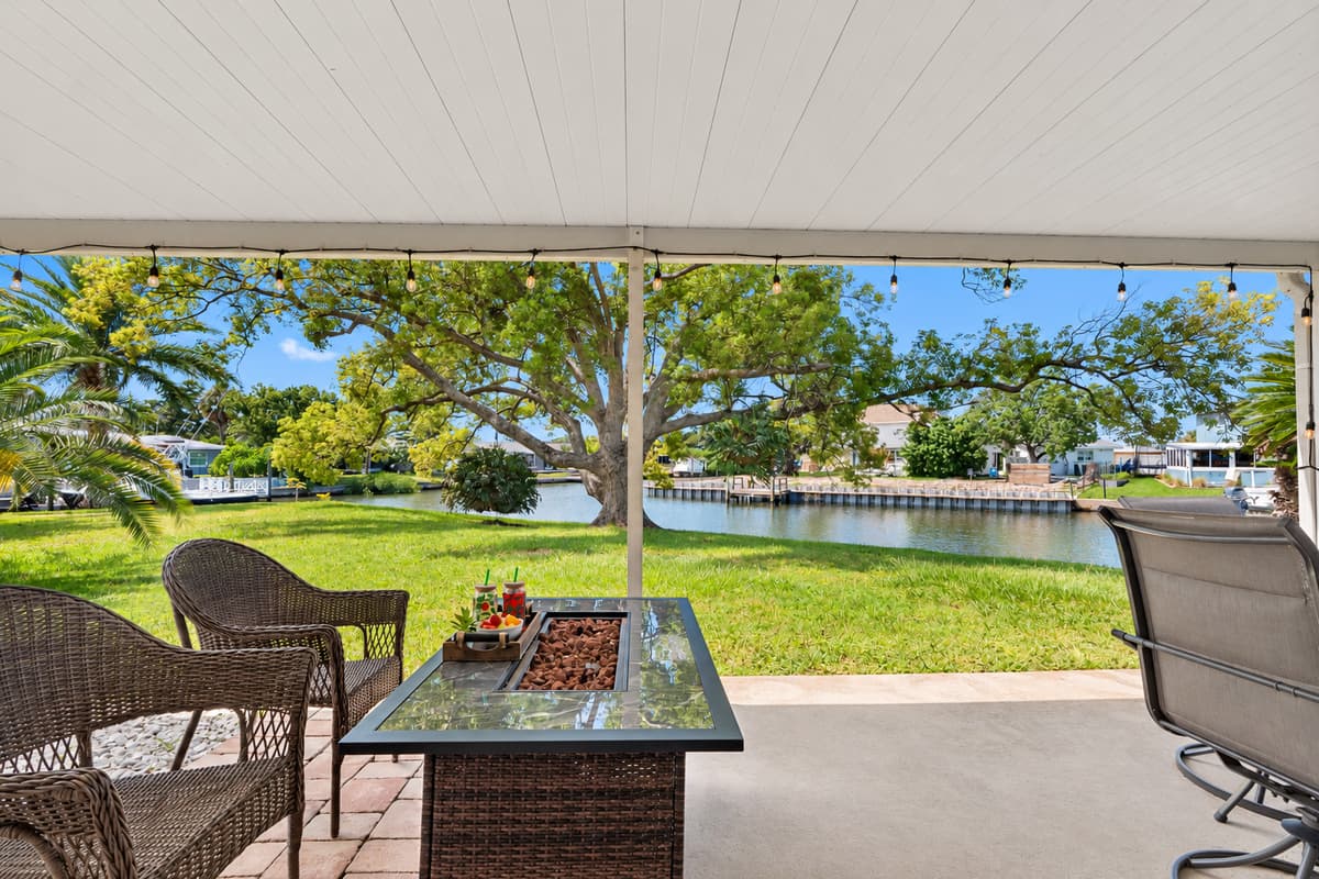 This covered patio offers a serene waterfront setting with lush greenery, perfect for relaxing by the canal and taking in the peaceful views.