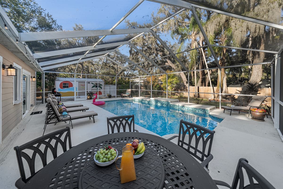 Enjoy outdoor dining by the pool with a shaded patio table, perfect for morning coffee, fresh fruit, or evening meals with family and friends.