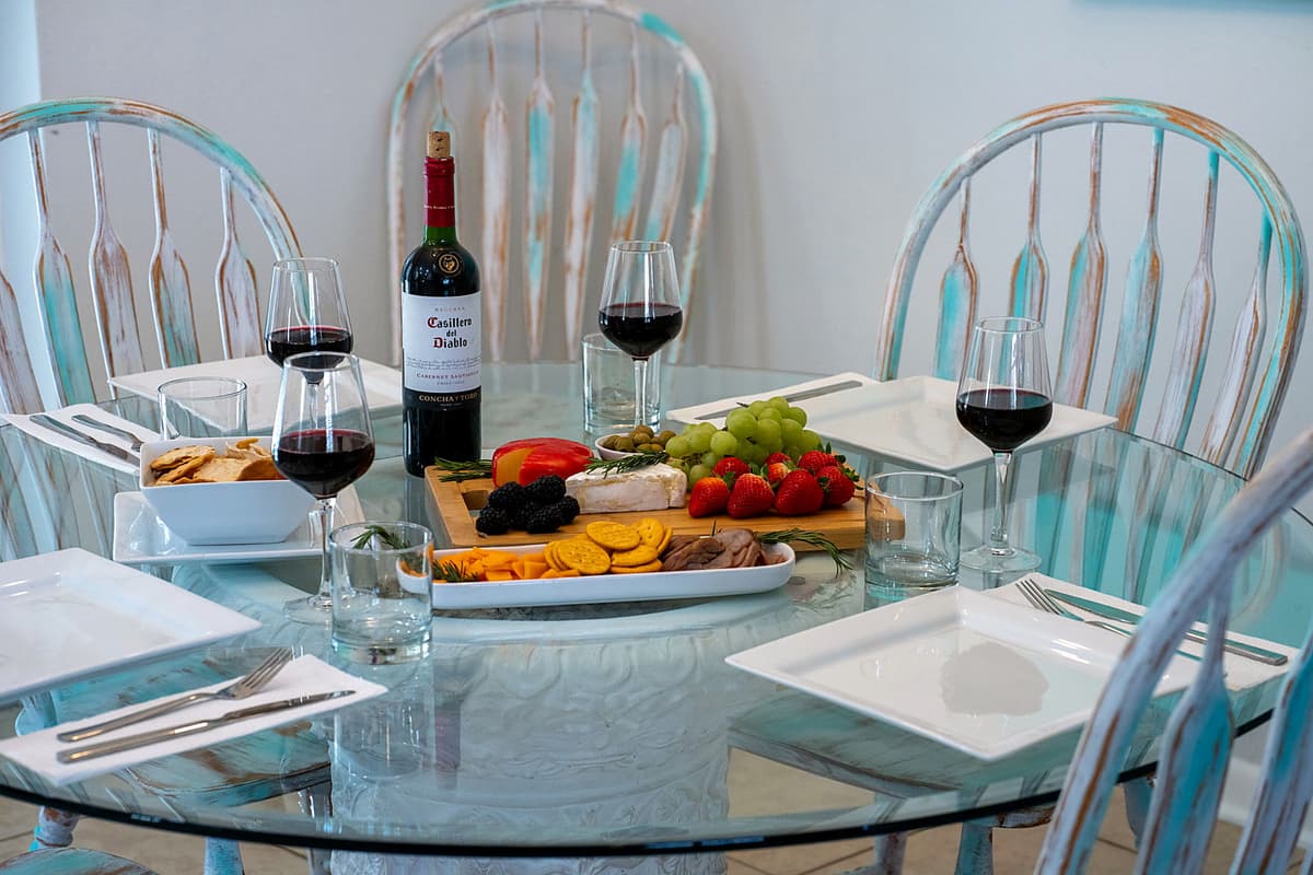 The sleek glass tabletop enhances the airy, beach-inspired atmosphere, allowing natural light to flow through and creating a relaxed yet sophisticated dining experience.