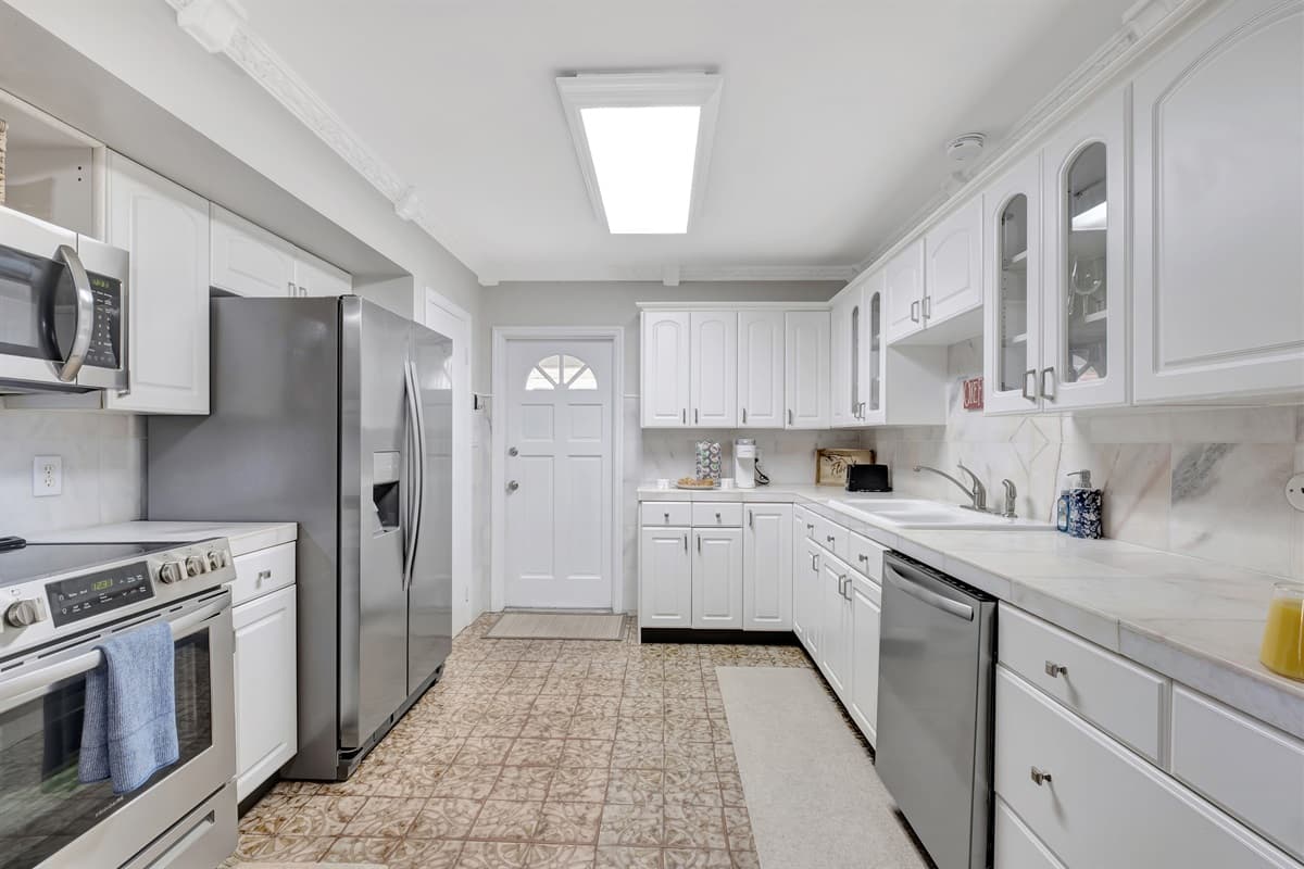 This culinary haven features pristine white-painted cupboards that gleam with timeless elegance, creating an airy and inviting atmosphere.