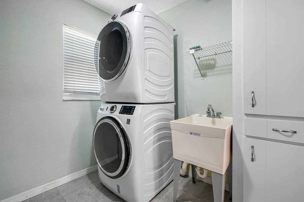 Designed for comfort and convenience, this laundry area features a modern front-load washer and dryer plus a deep sink for all your cleaning needs.
