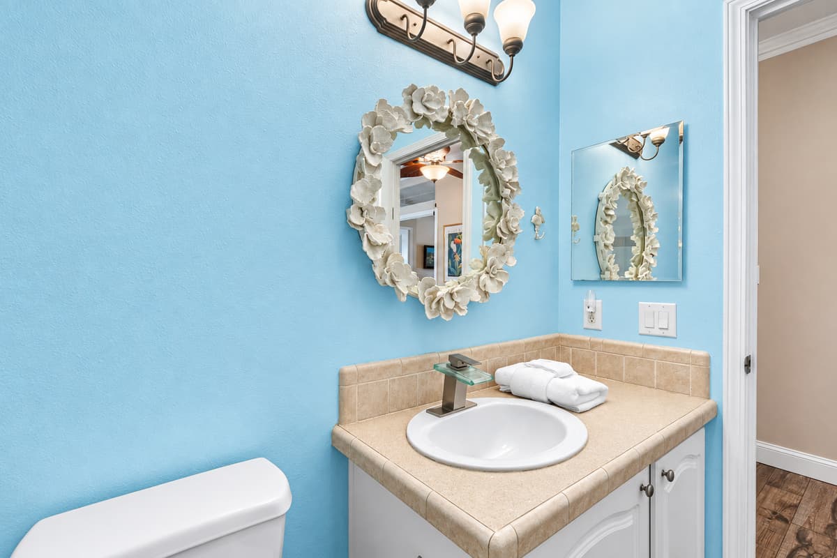 Bright and inviting, this bathroom includes a spacious tiled shower with sliding glass doors, a classic white vanity, and elegant lighting that adds warmth to the space.