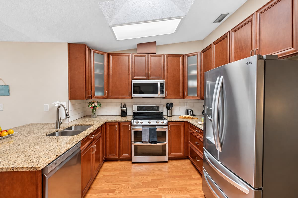The space includes a full-size refrigerator, oven, stove, microwave, dishwasher, and a coffee maker, as well as essentials like pots, pans, baking sheets, knives, cutting boards, and a variety of cooking tools.