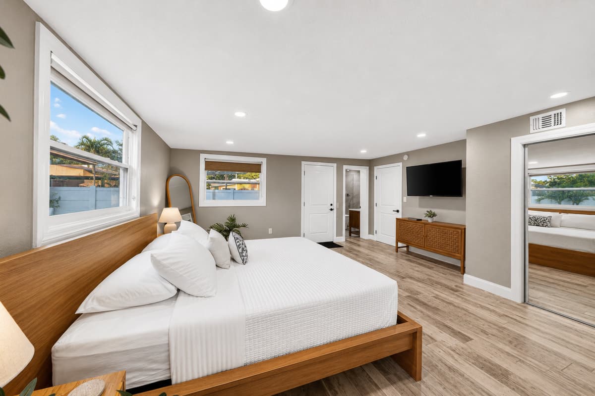 Spacious primary suite showcasing a king-size bed, TV, dresser, and generous open floor plan.