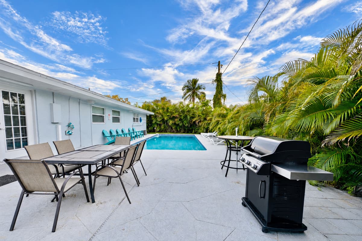 The backyard combines comfort and function, with sun loungers, dining space, and a modern barbecue.