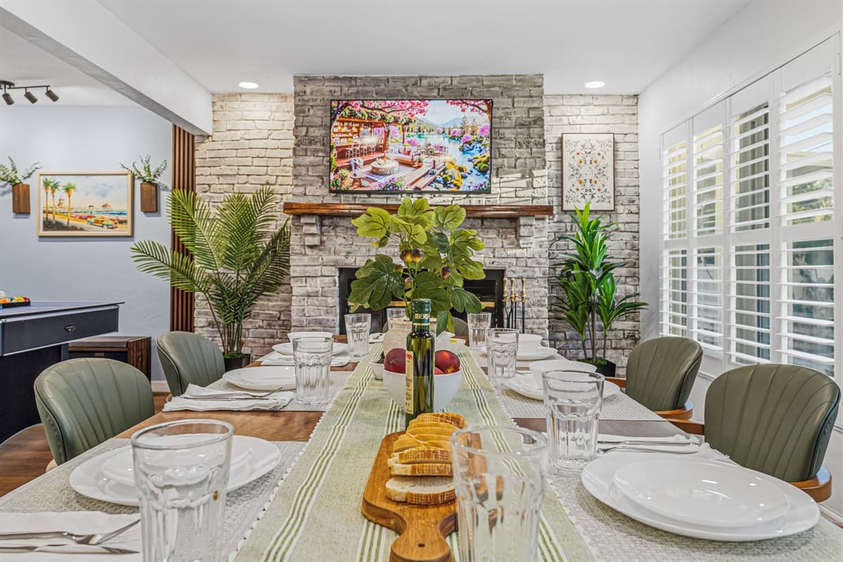 Dining table set near the fireplace, offering a warm and inviting atmosphere for group meals 
Table settings and food are for staging purposes only and are not included.