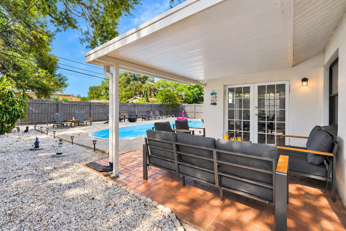 French doors open straight from the living room onto this patio, and the patio opens right onto the pool. Inside, outside, water — the whole house flows in one line, so the group never splits up during the day.