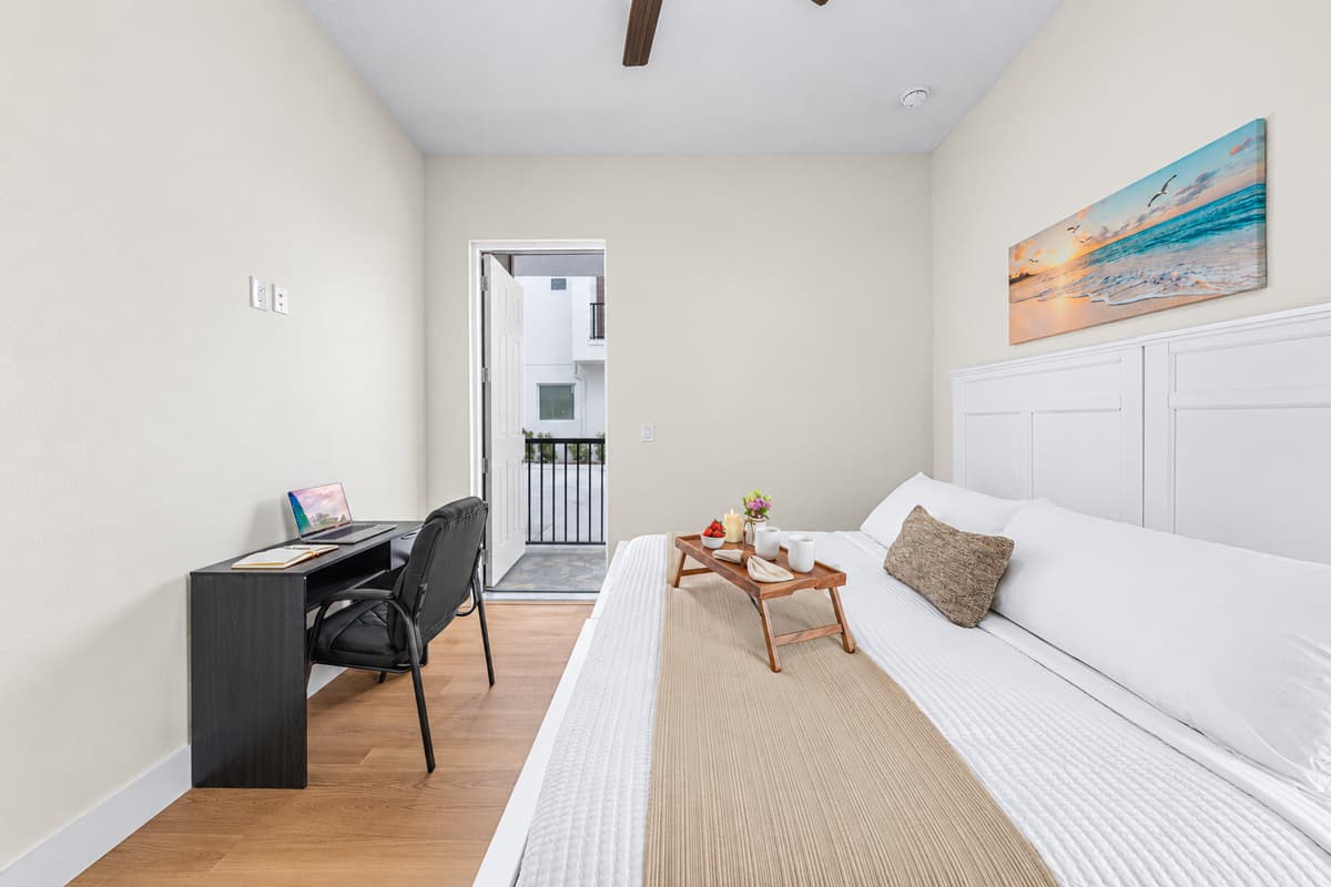 Bedroom 1 includes a workspace and direct access to the private covered patio.