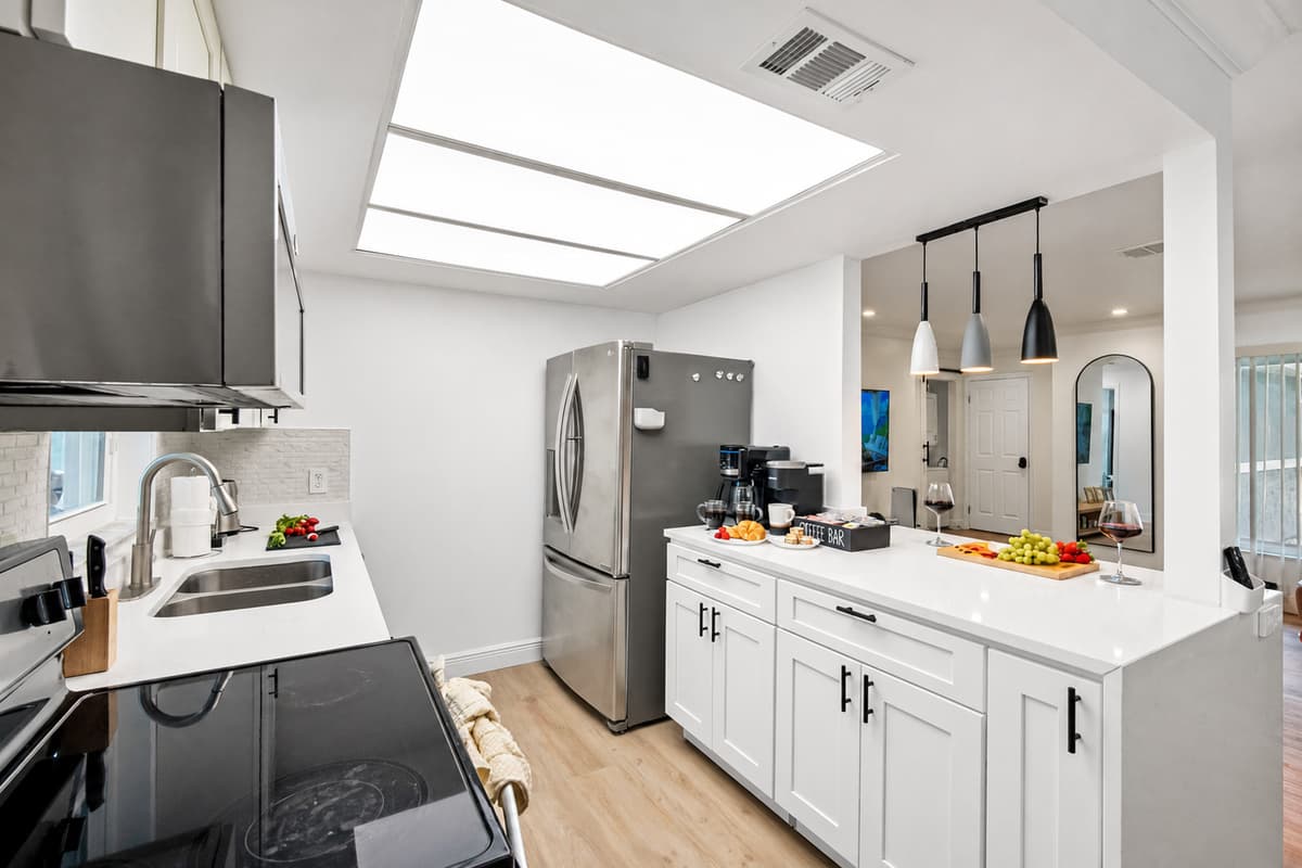 This modern kitchen features clean white cabinetry, quartz countertops, and stainless steel appliances for a fresh, polished look.