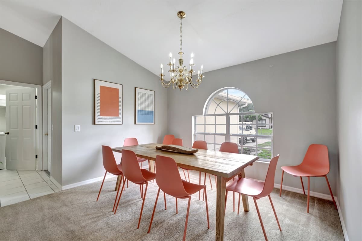 Above the table, a stunning chandelier hangs majestically, casting a soft glow that adds a touch of glamour to the space.