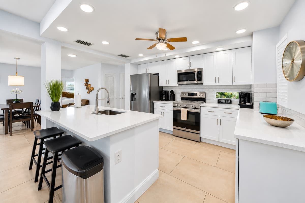 Fully equipped kitchen featuring stainless steel appliances, large island, and open dining flow.