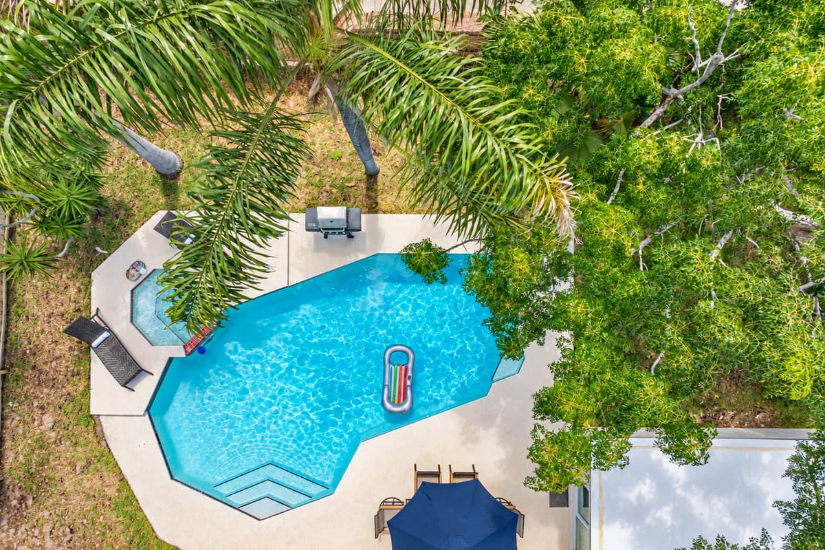The pool is a centerpiece of tranquility, surrounded by lush landscaping that enhances its serene ambiance.