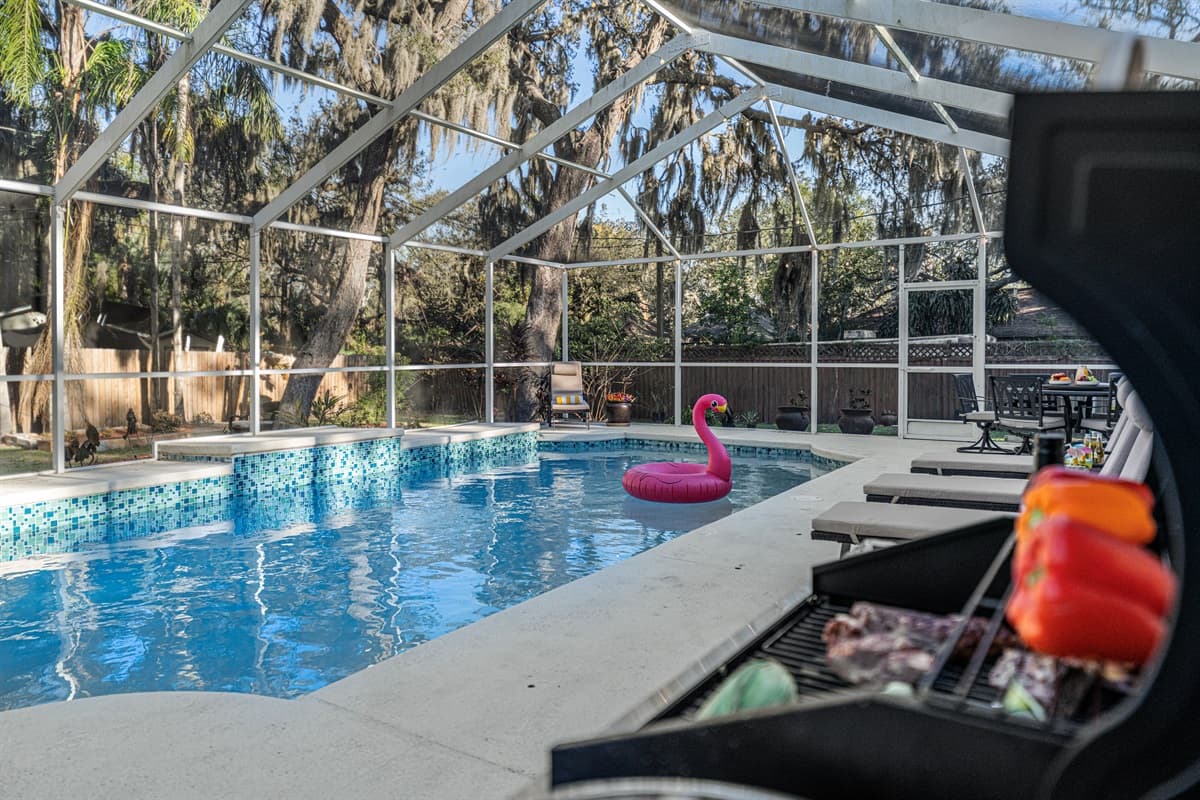 Take in the serene backyard setting featuring a crystal-clear private pool, screened enclosure, and peaceful wooded views for ultimate relaxation.