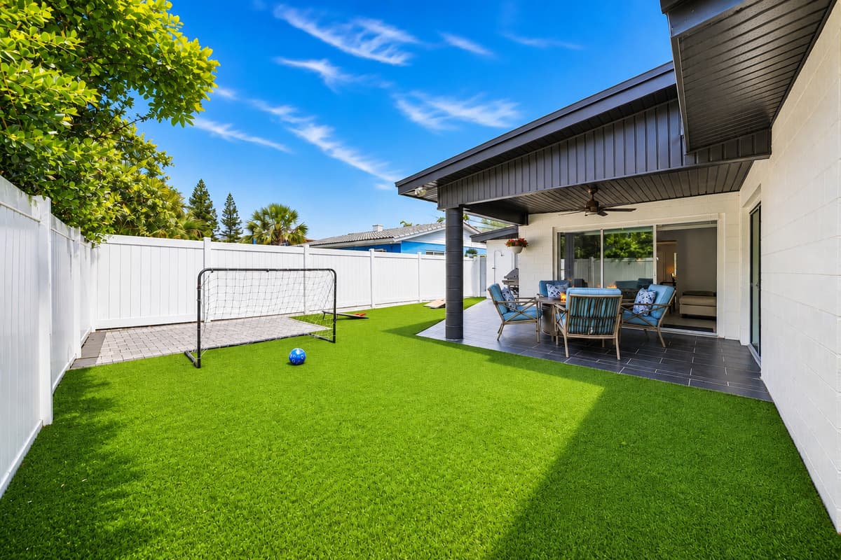 Spacious fenced backyard featuring a mini soccer goal and covered patio seating area.