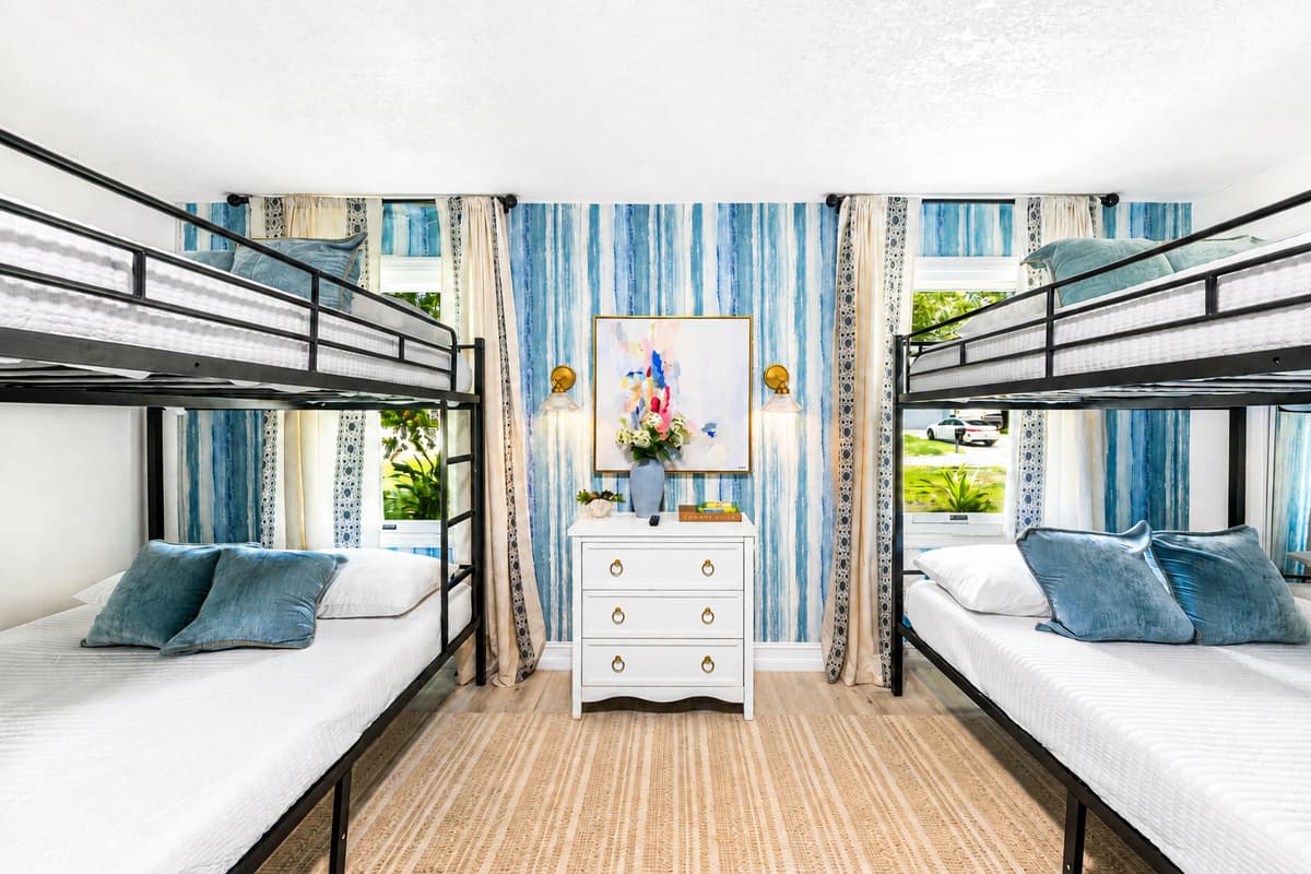 Two bunks facing a bright window, dresser between them. Four sleep here without anyone feeling stacked in.