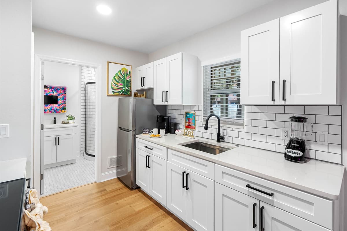 This sleek, all-white kitchen is a vision of contemporary design and functionality, crafted to cater to your every culinary need with style and precision.
