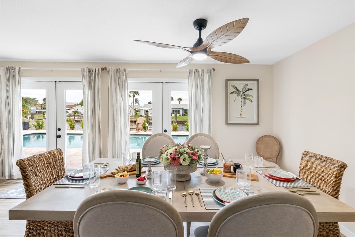 Natural textures and soft beige tones give this dining space a coastal charm, complemented by the warm overhead light fixture and modern wall art.