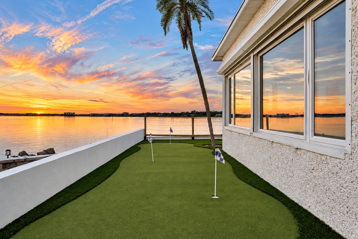 Sunset over the green. The putting green glows as the sun drops behind the bay. Sink one last putt before dinner.