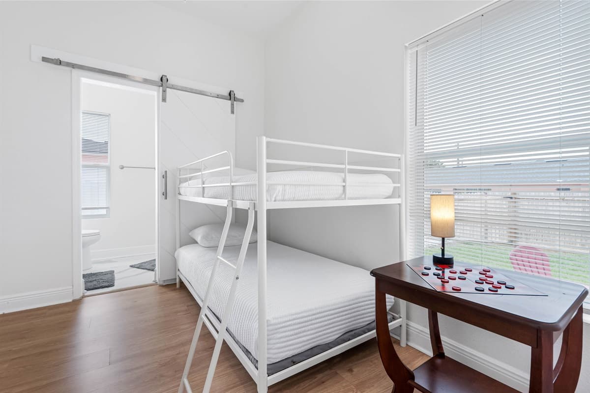 A cozy and well-appointed bunk bedroom that maximizes space without sacrificing comfort. Twin beds, neutral décor, and soft lighting create a calm environment, while the nearby bathroom access makes it especially convenient for families.