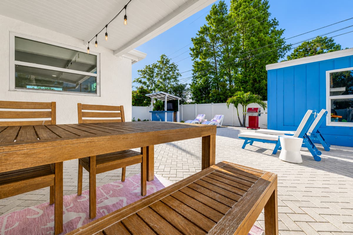 Covered outdoor dining area with a large picnic-style table, providing a shaded space for al fresco meals beside the pool.