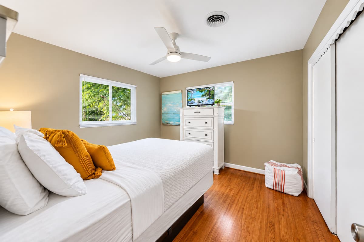 Spacious guest room with a dresser, TV, and calming neutral décor for a restful stay.