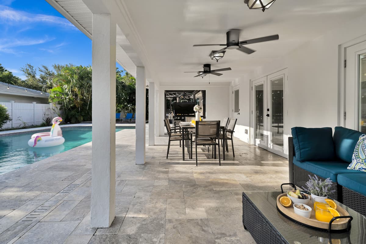 Teal outdoor sofas and a dining set share the covered lanai with pool views, plenty of room for the whole group to relax together