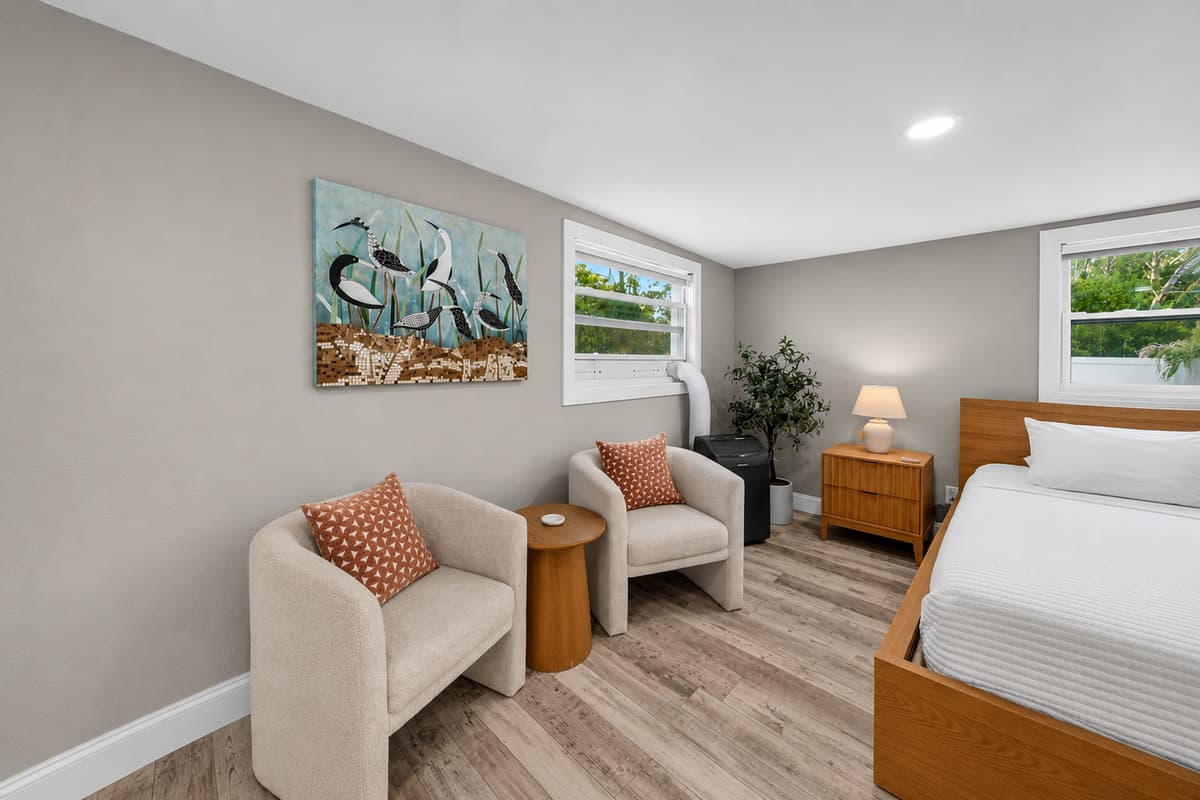 Cozy seating nook within the primary suite, complete with accent chairs, bedside tables, and coastal-inspired artwork.