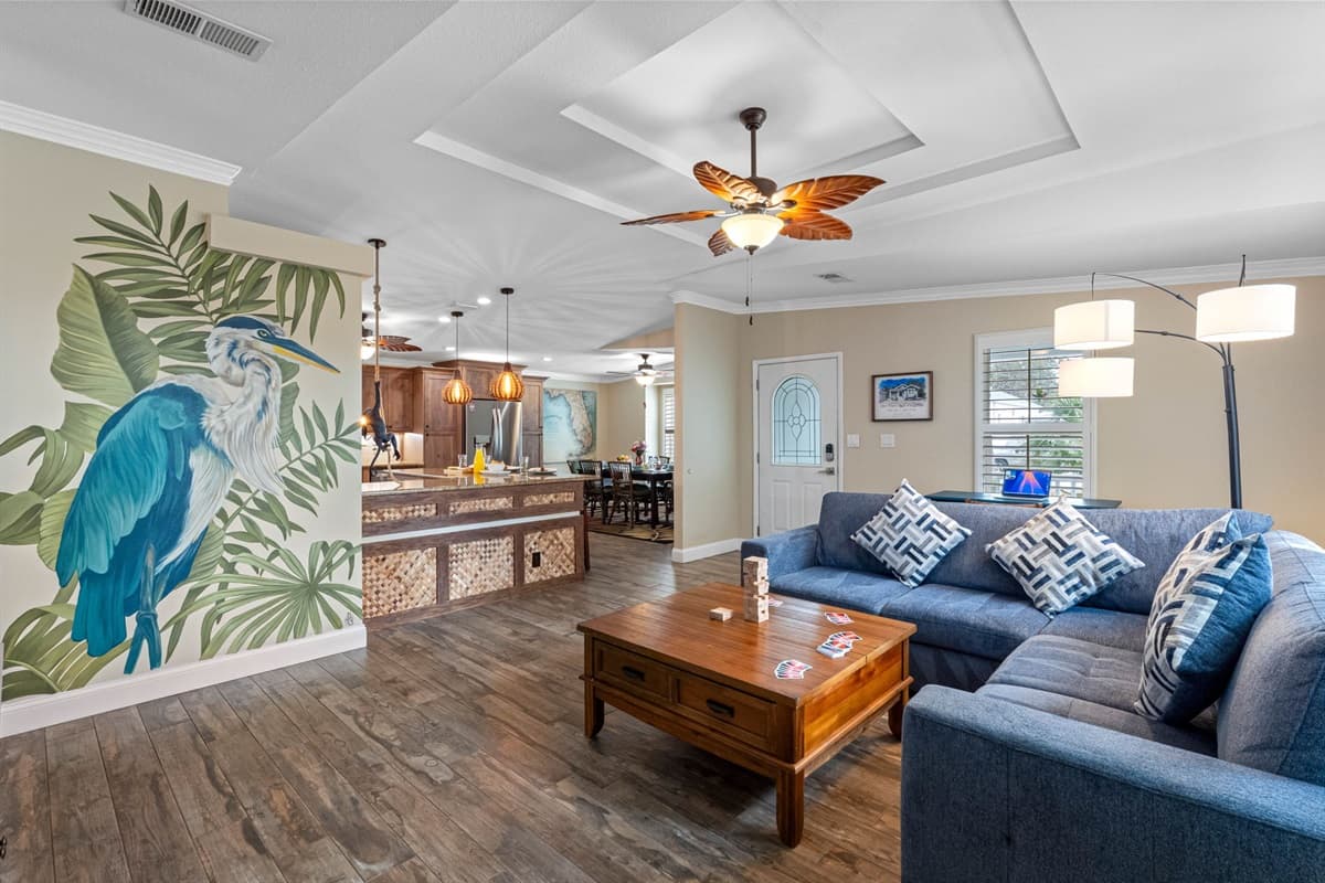 Experience Florida living at its finest in this stylish living space, complete with a large smart TV, spacious sectional, and beautiful tropical artwork.