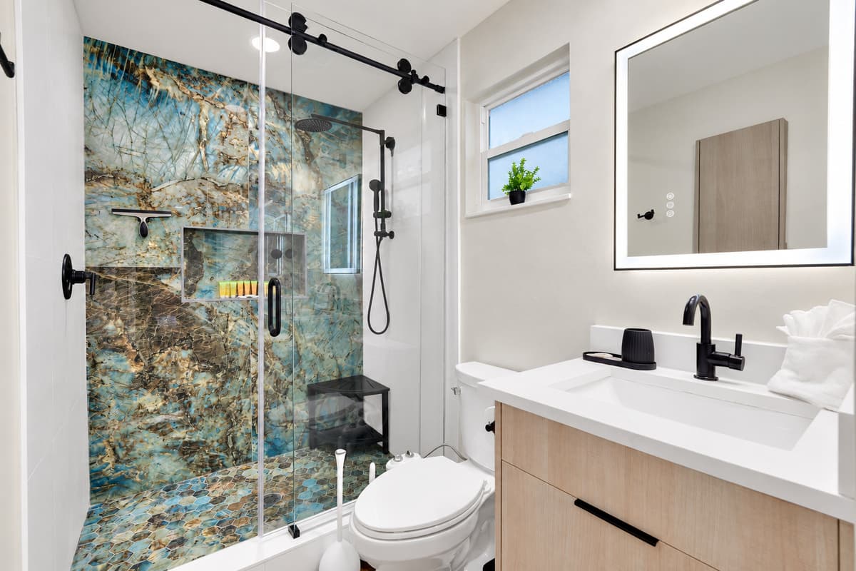 A shower this good makes the whole trip easier. Full glass enclosure, dramatic stone-look walls, lit mirror and a wide vanity — private, bright, and one of seven and a half bathrooms in the house.