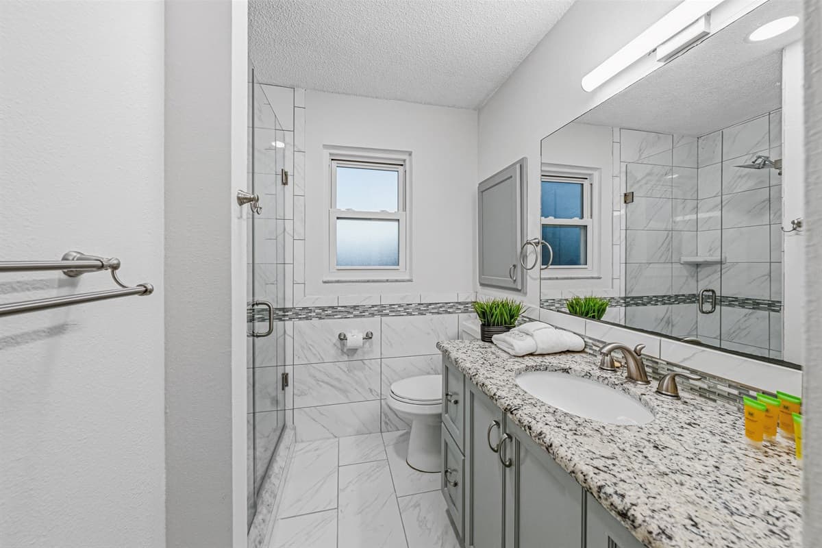 Updated bathroom with granite countertop, walk-in shower, and bright, clean finishes 
