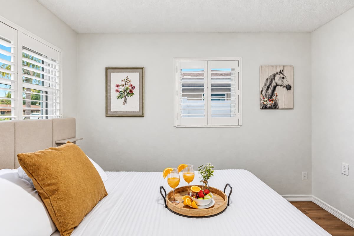 Close-up of king bed with decorative accents and cozy styling—perfect for unwinding after a long day 
Tray and food setup shown are for staging purposes only and are not included.