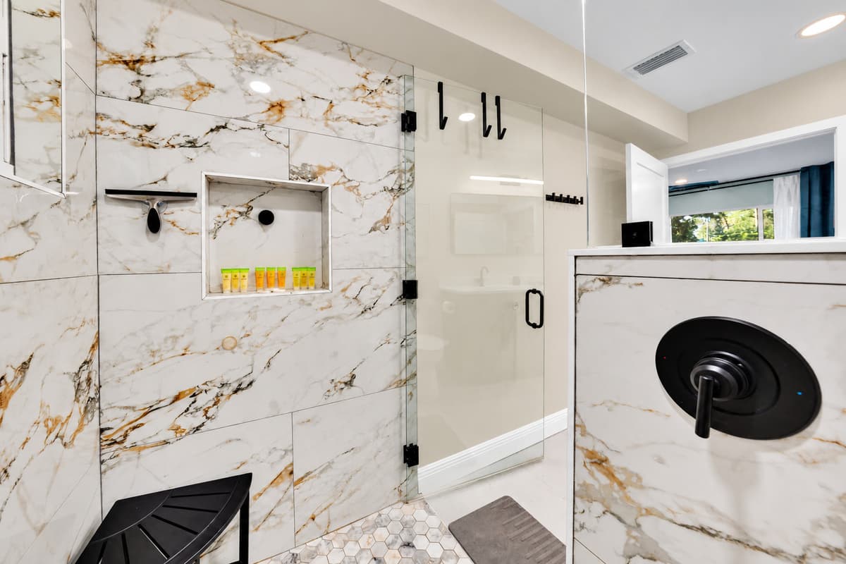 The most useful bathroom in the house. Walk-in shower behind glass, marble-look surrounds and a front-loading machine, so sandy clothes never travel through the bedrooms.