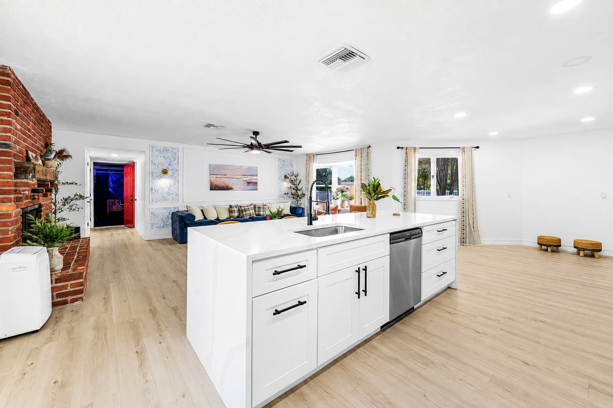 The island sits in the middle of everything — kitchen behind you, living room ahead, the whole house in one view.