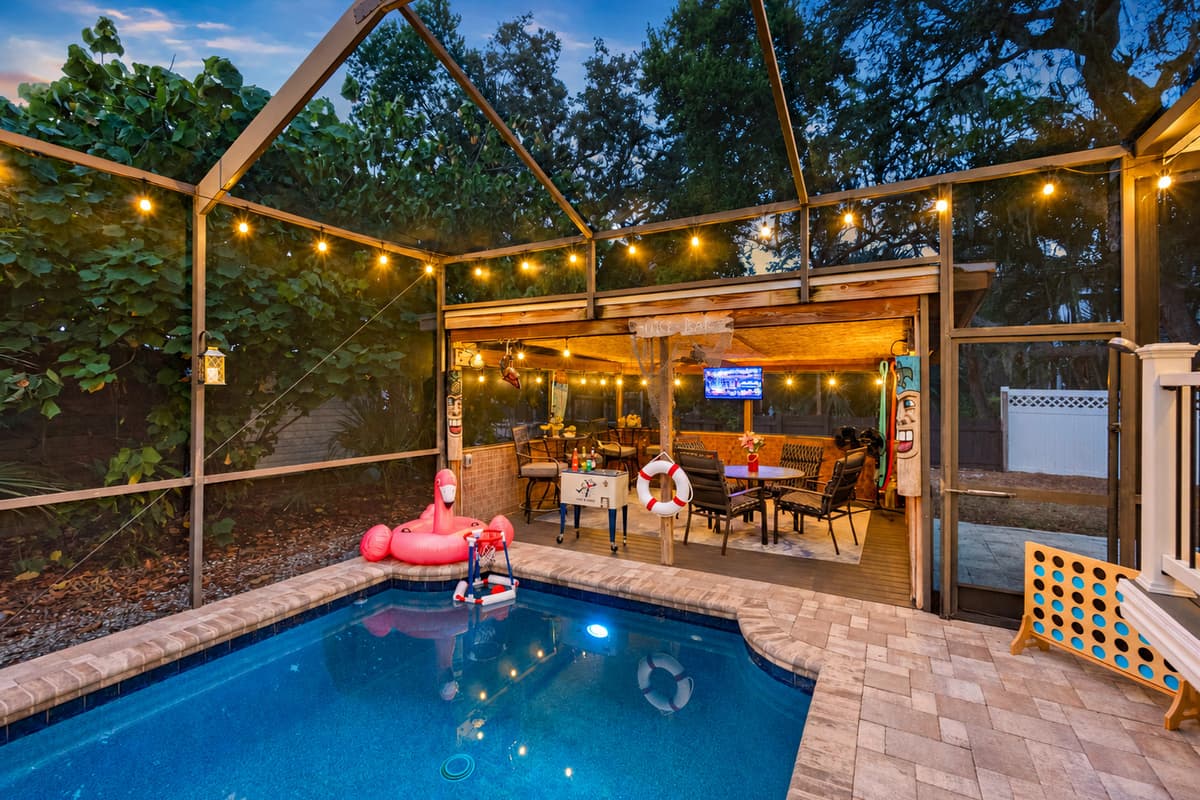 A beautifully lit pool creates the perfect evening ambiance, with cozy seating and a festive outdoor bar just steps away.