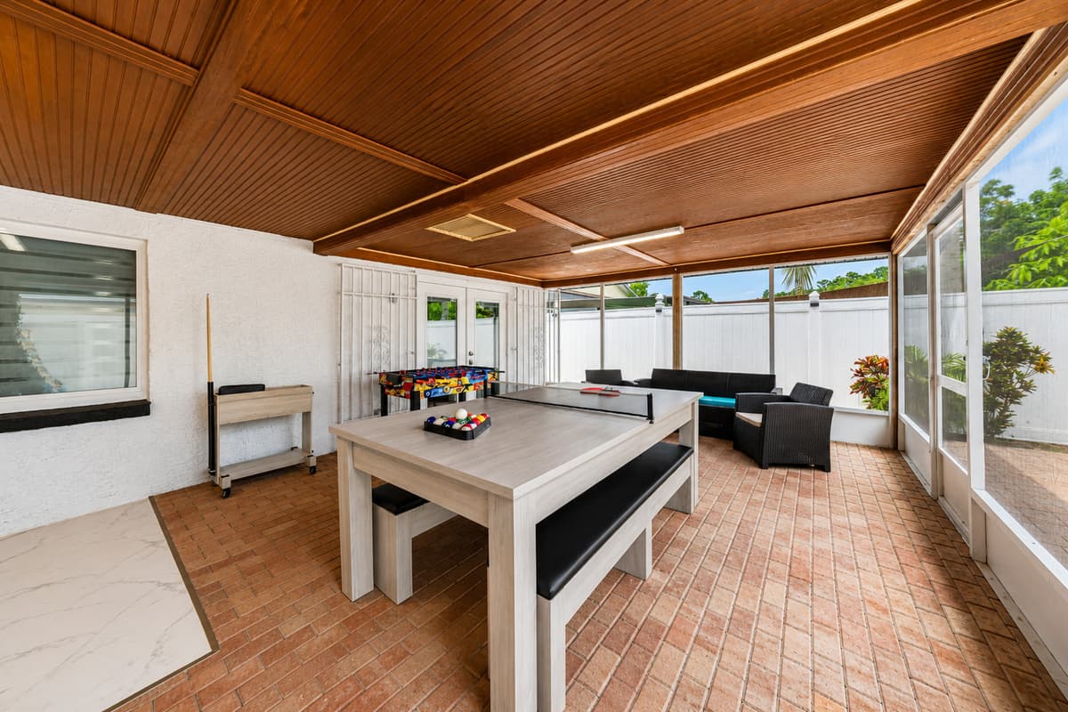 Expansive covered patio designed for entertainment, featuring a pool table, comfortable seating, and plenty of room to gather.